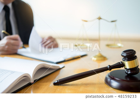 Male lawyer working with contract papers and reading law book in 48159233