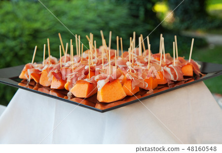 Melon cut into portionts and ham, in a banquet 48160548