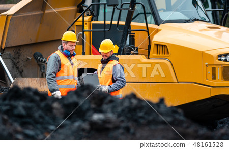 Worker with a plan and a clipboard discussing things in quarry 48161528