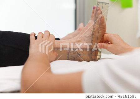 Doctor or physiotherapist meausuring active range Doctor or physiotherapist meausuring active range 48161583
