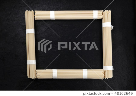 A photo of individually wrapped portions of udon noodles, shot from above, forming a frame on a A photo of individually wrapped portions of udon noodles, shot from above, forming a frame on a 48162649