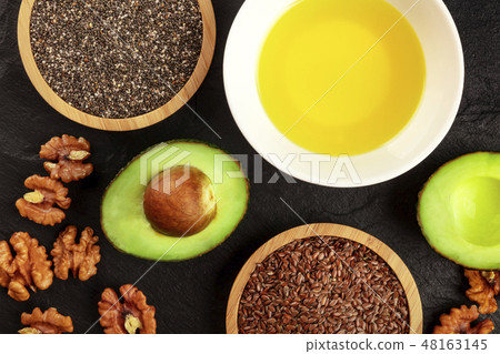 An overhead photo of the ingredients of a healthy vegan omega 3 diet. Avocado, nuts, chia and flax 48163145