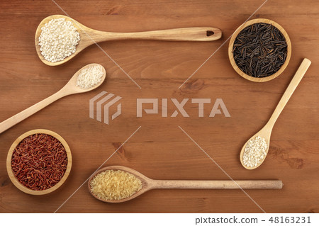 A photo of various types of rice, shot from the top on a rustic wooden background with copy space 48163231