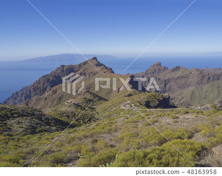 view on asfalt road to village Masca with green hills, sharp mountain peaks, sea horizon and clear view on asfalt road to village Masca with green hills, sharp mountain peaks, sea horizon and clear 48163958