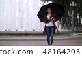 girl with an umbrella in the park on a background of a fountain 48164203