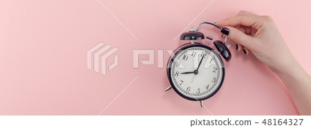 Female hand with alarm clock. Morning concept Female hand with alarm clock. Morning concept 48164327