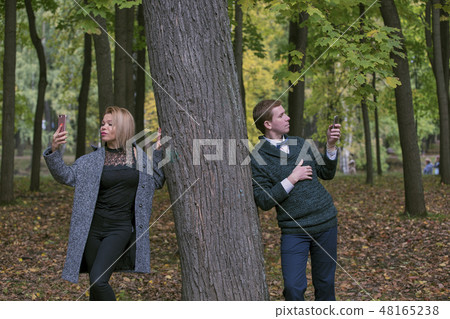 Mobile phone addiction concept - couple using at their mobile phone while on a date outdoor 48165238