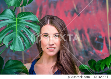 Close up portrait of a young brunette lady, wearing blue dress. The girl posing, looking at the 48165351