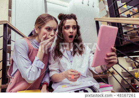 Impressed girls being terrified with content on the tablet Impressed girls being terrified with content on the tablet 48167261
