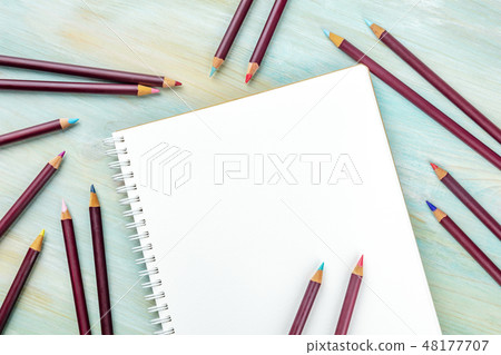An overhead photo of a shetchbook with many different color pencils around it, shot from above on a An overhead photo of a shetchbook with many different color pencils around it, shot from above on a 48177707