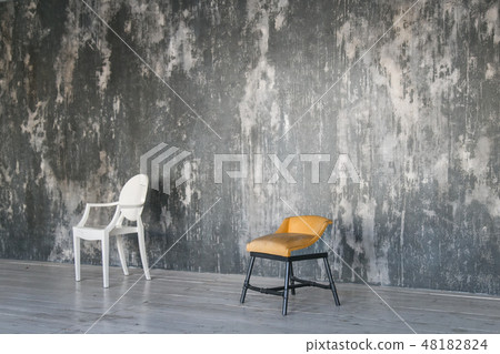 Two chairs against the gray concrete wall. Room in loft style. Wooden floor. Daylight. Free space 48182824