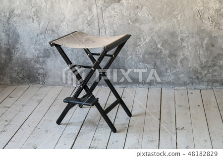 Director's chair on concrete wall background. Loft room. Wooden floor. Daylight. Free space for text 48182829