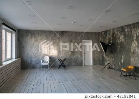 Modern light loft-style room with designer chairs and lighting. Gray walls with the texture of the Modern light loft-style room with designer chairs and lighting. Gray walls with the texture of the 48182841