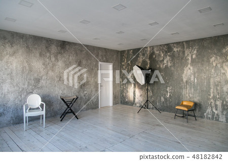 Modern light loft-style room with designer chairs and lighting. Gray walls with the texture of the Modern light loft-style room with designer chairs and lighting. Gray walls with the texture of the 48182842