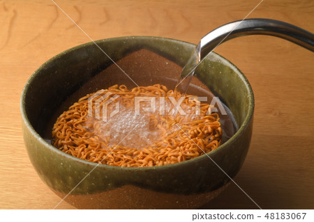 Pour hot water into instant noodles 48183067