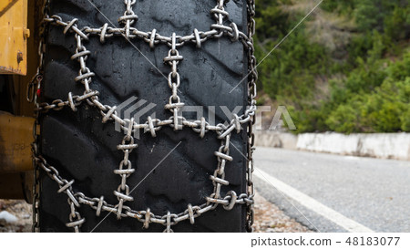 Front loader for snow removal with metal snow chains on wheels. Snow removal in the mountains. Front loader for snow removal with metal snow chains on wheels. Snow removal in the mountains. 48183077