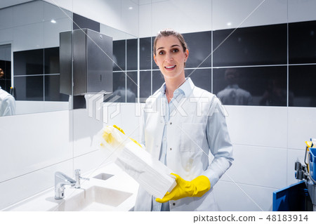 Janitor woman changing paper towels in public restroom Janitor woman changing paper towels in public restroom 48183914