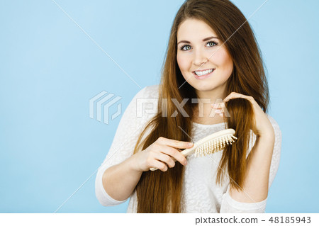 Happy woman brushing her hair Happy woman brushing her hair 48185943