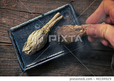 Man burning white sage incense 48194929