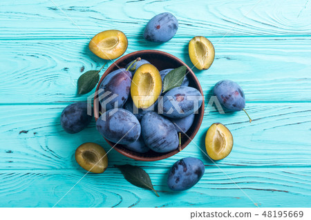 Fresh plums in bowl on wooden table 48195669