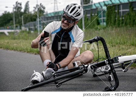 Injured biker holding smartphone calling rescue Injured biker holding smartphone calling rescue 48195777