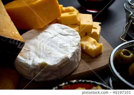 Close up on different kinds of cheese on wooden board on black table Close up on different kinds of cheese on wooden board on black table 48197101