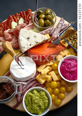 Antipasti board with various cheese and meat snacks with hummus and olives on wooden round board 48197159