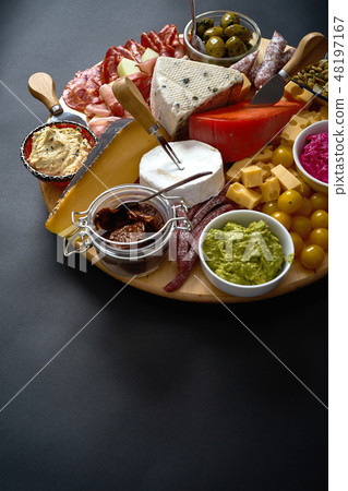 Antipasti board with various cheese and meat snacks with hummus and olives on wooden round board 48197167
