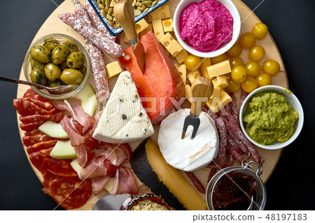 Antipasti board with various cheese and meat snacks with hummus and olives on wooden board Antipasti board with various cheese and meat snacks with hummus and olives on wooden board 48197183