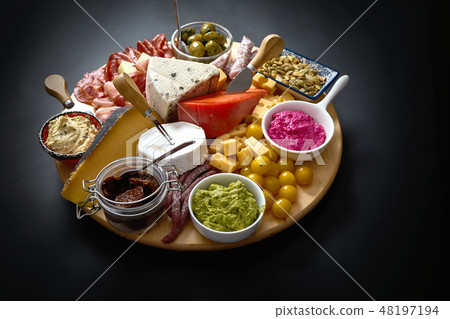 Antipasti board with various cheese and meat snacks with hummus and olives on wooden round board 48197194