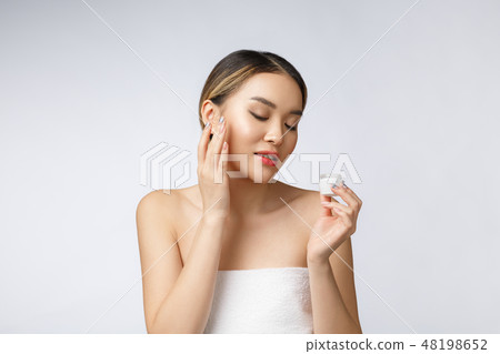Asian woman applying cosmetic cream on skin on isolated white background Asian woman applying cosmetic cream on skin on isolated white background 48198652
