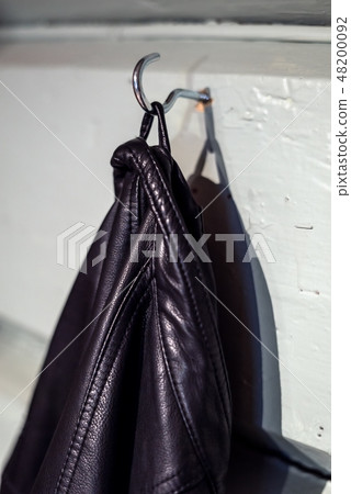 A black leather jacket hanging from a simple hook 48200092