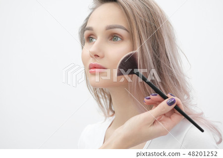 Make-up artist makes makeup beautiful blonde girl on a white background. Close-up hands with brush Make-up artist makes makeup beautiful blonde girl on a white background. Close-up hands with brush 48201252