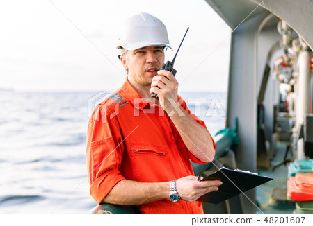 Deck Officer on deck of offshore vessel holds VHF walkie-talkie radio 48201607