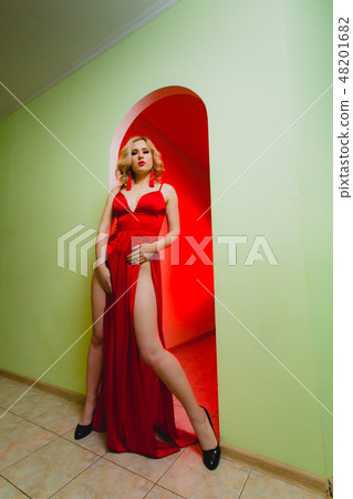 Attractive blonde model in the red dress with high slit and long naked legs 48201682