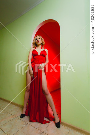 Young sexy blonde woman in the red dress with high slit Young sexy blonde woman in the red dress with high slit 48201683