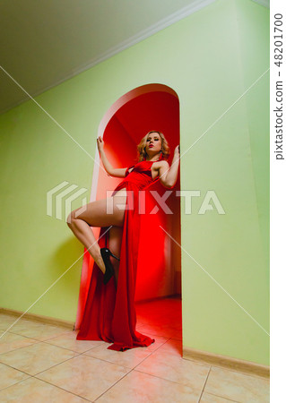 Attractive blonde model in the red dress with high slit and long naked legs 48201700