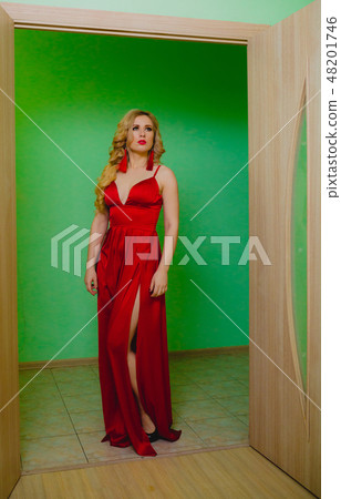 Attractive blonde model in the red dress posing in a studio Attractive blonde model in the red dress posing in a studio 48201746