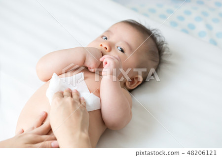 Mom cleaning up and wipe body baby by wet tissue  48206121