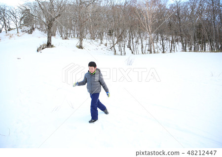 Child walking on snowy road 48212447