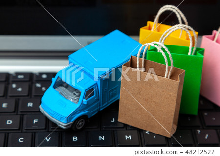 Delivery of orders from the online store. Shopping bags on the laptop keyboard and courier delivery Delivery of orders from the online store. Shopping bags on the laptop keyboard and courier delivery 48212522