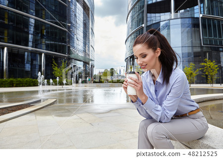 Beautiful young businesswoman with a disposable coffee cup Beautiful young businesswoman with a disposable coffee cup 48212525