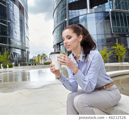 Beautiful young businesswoman with a disposable coffee cup Beautiful young businesswoman with a disposable coffee cup 48212526