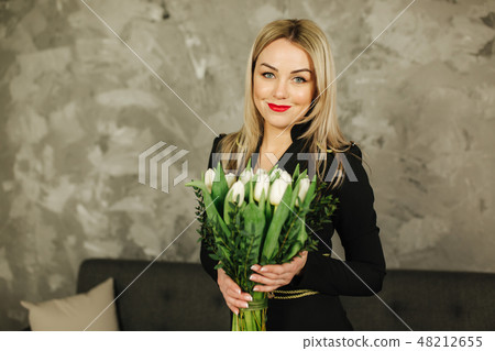 Beautiful mother hold a bouquet of white tulips on 8th of march. Flowers in woman's hand. Blond hair Beautiful mother hold a bouquet of white tulips on 8th of march. Flowers in woman's hand. Blond hair 48212655