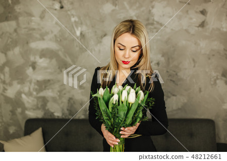Beautiful mother hold a bouquet of white tulips on 8th of march. Flowers in woman's hand. Blond hair Beautiful mother hold a bouquet of white tulips on 8th of march. Flowers in woman's hand. Blond hair 48212661