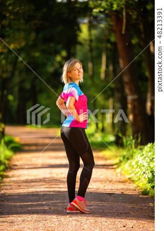 Photo from back of sporty woman standing in park among trees on summer. Photo from back of sporty woman standing in park among trees on summer. 48213391