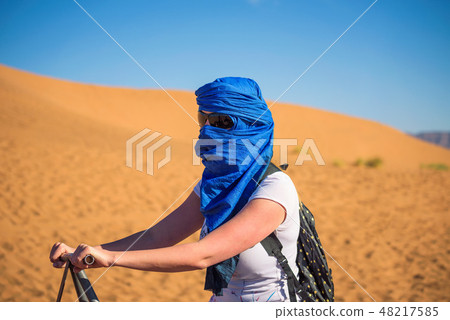 Tourist rides a camel through the sand dunes in the Sahara desert 48217585