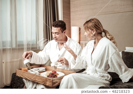 Blonde-haired wife wearing white bathrobe talking to husband Blonde-haired wife wearing white bathrobe talking to husband 48218323