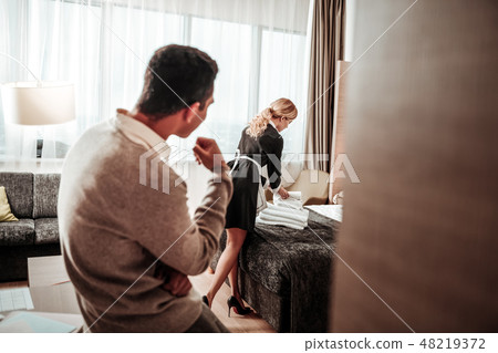 Maid working in room while client standing and watching her Maid working in room while client standing and watching her 48219372