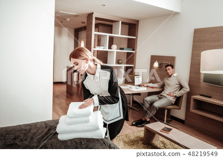 Pleasant hard-working housekeeper bringing new white towels Pleasant hard-working housekeeper bringing new white towels 48219549